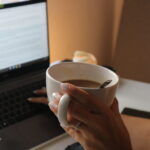 Frau entwickelt eine Content-Strategie am Laptop mit Tasse in der Hand