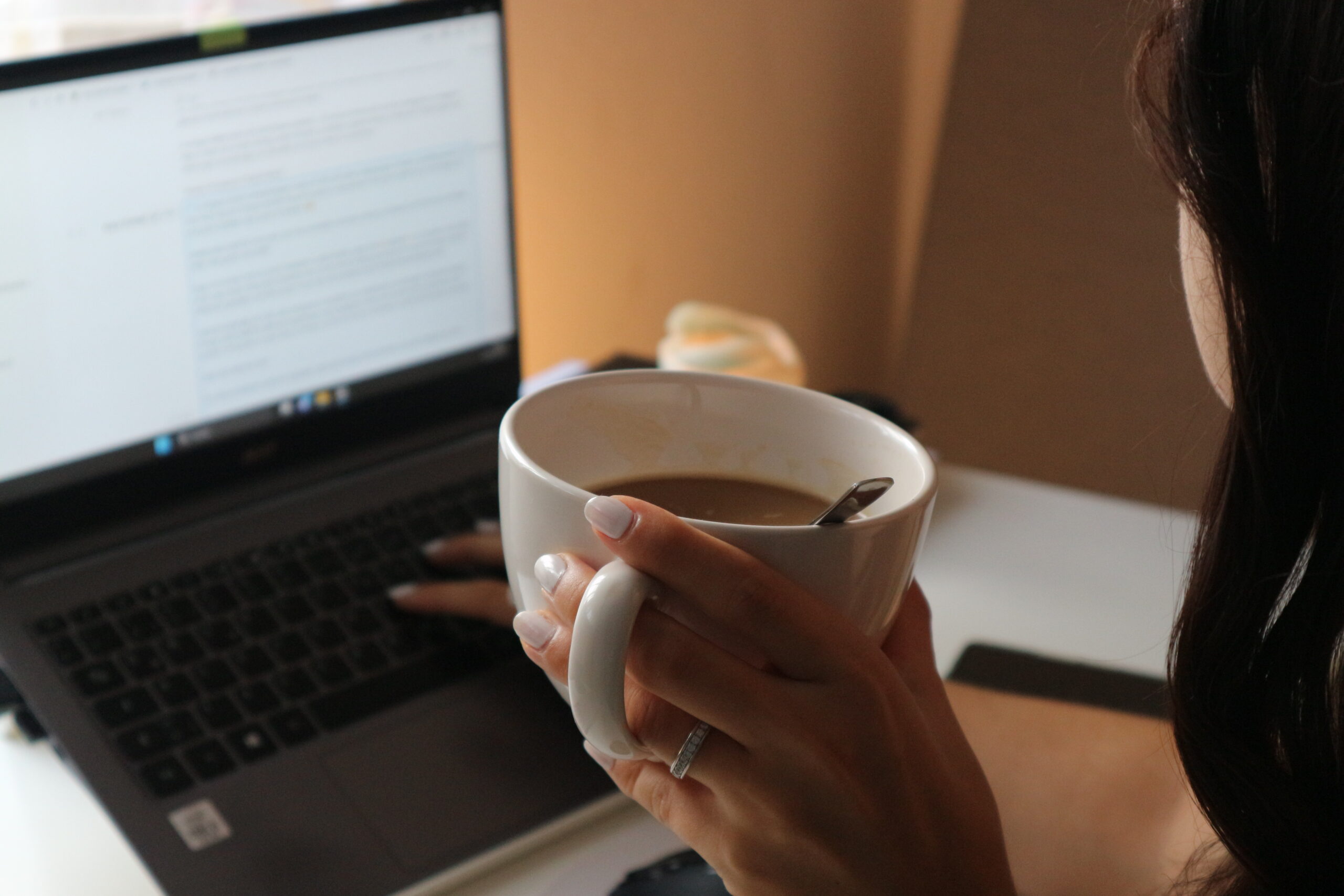 Frau entwickelt eine Content-Strategie am Laptop mit Tasse in der Hand