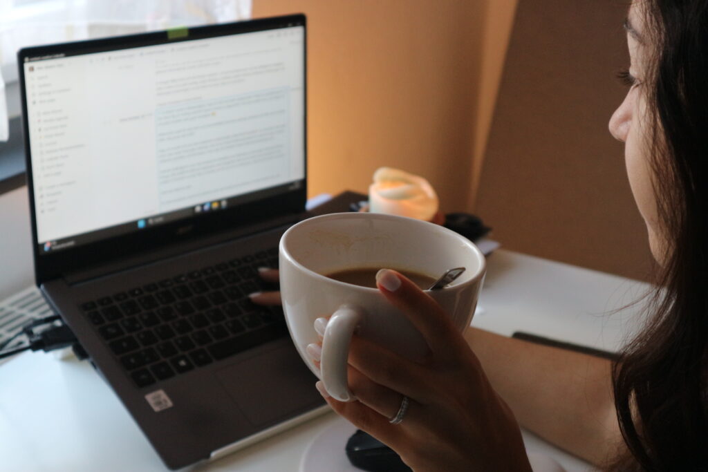 Alex Giannelli am Laptop mit Kaffee in der Hand